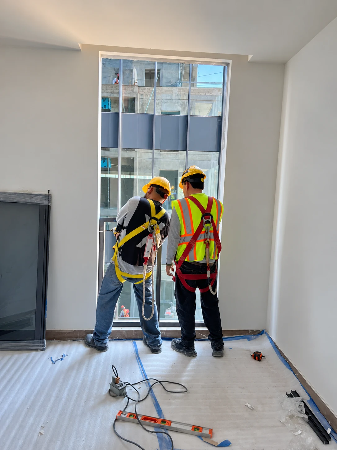 Dos instaladores trabajando en un vano de aluminio y vidrio.